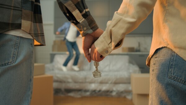 Couple holding house keys with moving boxes as a child runs in the background, illustrating relocation matters handled by Brown Family Law