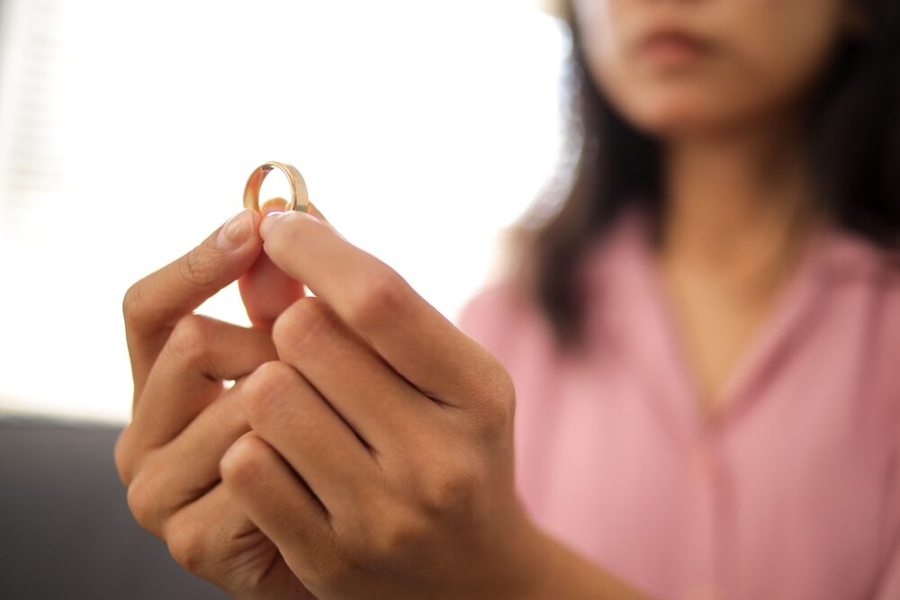 Woman holding her wedding ring reflecting on divorce, a matter handled by the divorce lawyers at Brown Family Law